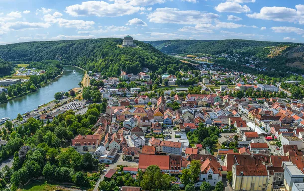 Panorama einer Stadtlandschaft mit Fluss und Hügel im Hintergrund.