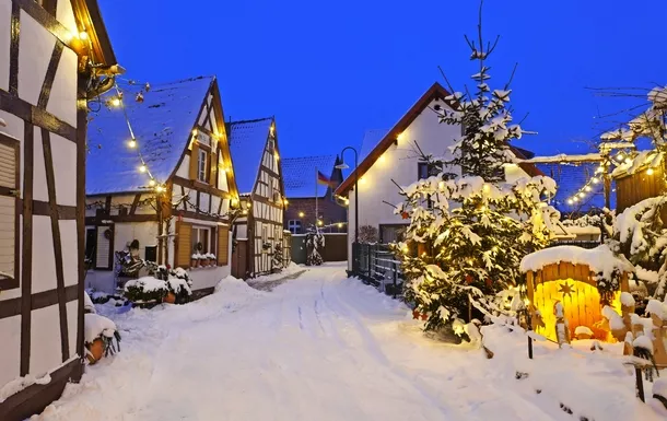 Verschneite Dorfstraße mit Fachwerkhäusern und weihnachtlicher Beleuchtung