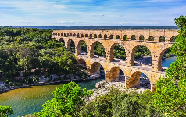 Pont du Gard, römischer Aquädukt über einen Fluss in bewaldeter Landschaft.