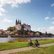 Zwei Radfahrer auf Radweg an der Elbe, im Hintergrund die Albrechtsburg in Meißen.